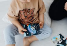 A young child sits on the floor assembling a space-themed puzzle piece.