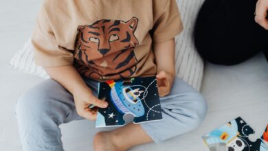 A young child sits on the floor assembling a space-themed puzzle piece.
