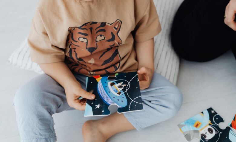 A young child sits on the floor assembling a space-themed puzzle piece.