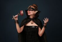A woman dressed as a vampire enjoying Halloween with a heart prop in hand.