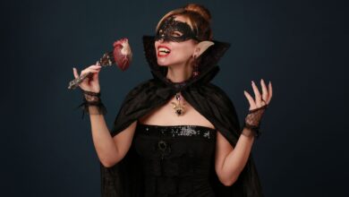 A woman dressed as a vampire enjoying Halloween with a heart prop in hand.