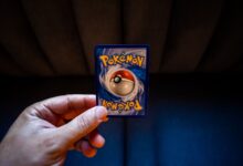 Crop unrecognizable person demonstrating collectible card dedicated to fictional creatures on dark background
