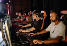 A group of focused young gamers playing in an intense esports tournament indoors.