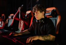 Competitive gamers in an esports tournament concentrating deeply in dimly lit setting.
