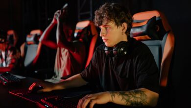 Competitive gamers in an esports tournament concentrating deeply in dimly lit setting.