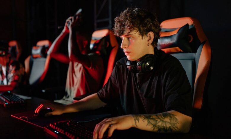 Competitive gamers in an esports tournament concentrating deeply in dimly lit setting.
