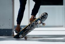 A skateboarder performing a trick indoors with stylish footwear and graffiti skateboard design.