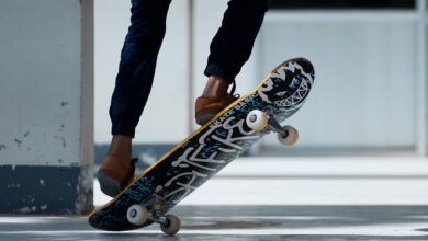 A skateboarder performing a trick indoors with stylish footwear and graffiti skateboard design.