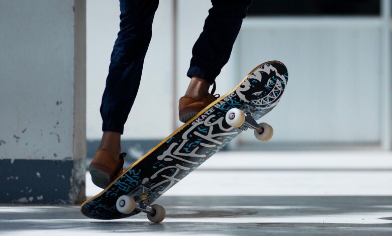 A skateboarder performing a trick indoors with stylish footwear and graffiti skateboard design.