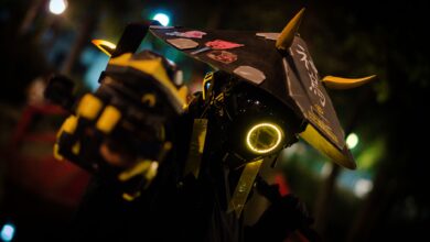 A person in neon cyberpunk costume poses dramatically at night.