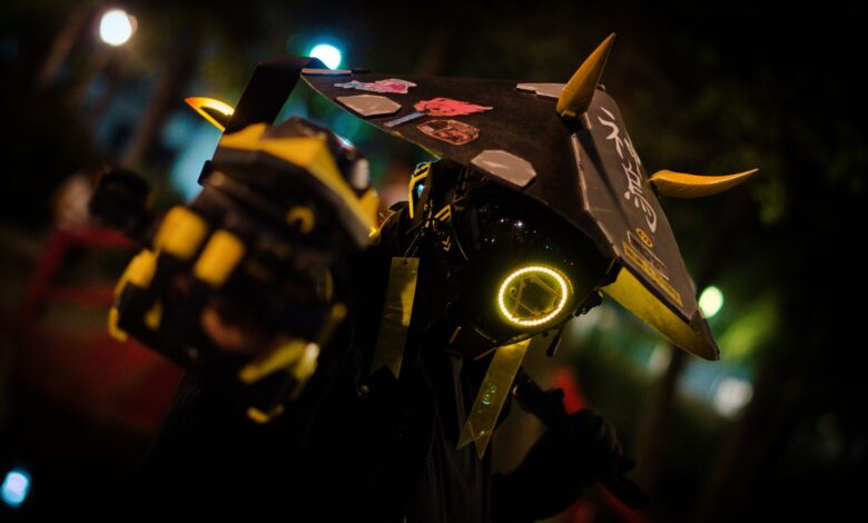 A person in neon cyberpunk costume poses dramatically at night.