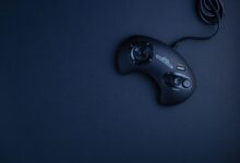 Navy blue vintage game console controller photographed from above on a dark background.