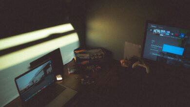 Dark room with a laptop and gaming console creating a moody tech atmosphere.