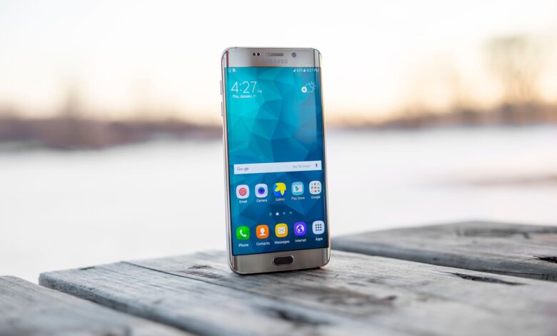 Samsung smartphone placed on a wooden surface outdoors during sunset.
