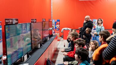 A lively group enjoys gaming at a Nintendo event in Zagreb, featuring multiple screens and vibrant atmosphere.