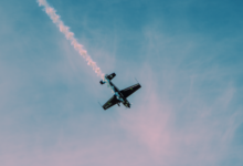 Dramatic stunt airplane showcasing aerobatics with a smoke trail against a clear sky.
