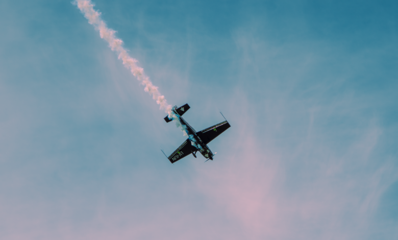 Dramatic stunt airplane showcasing aerobatics with a smoke trail against a clear sky.