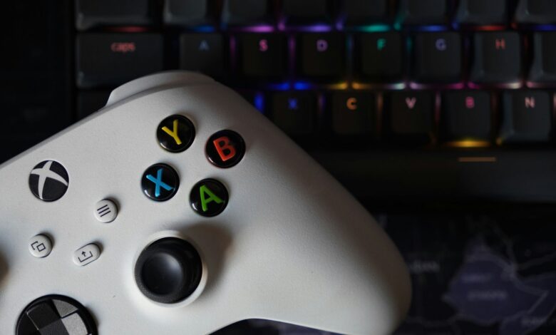 Game controller beside illuminated RGB keyboard, highlighting technology and gaming equipment.