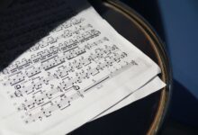 A detailed view of sheet music placed on a drum under soft sunlight, creating artistic shadows.