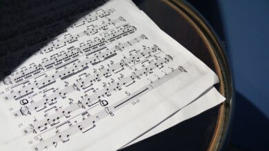 A detailed view of sheet music placed on a drum under soft sunlight, creating artistic shadows.