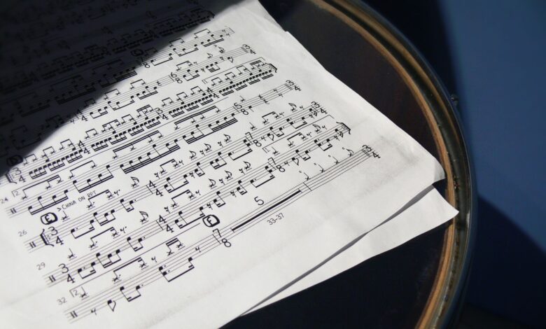 A detailed view of sheet music placed on a drum under soft sunlight, creating artistic shadows.