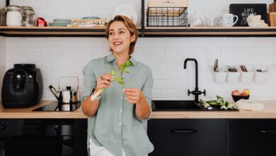 Smiling woman with vegetables in a stylish kitchen showcasing modern interior design.