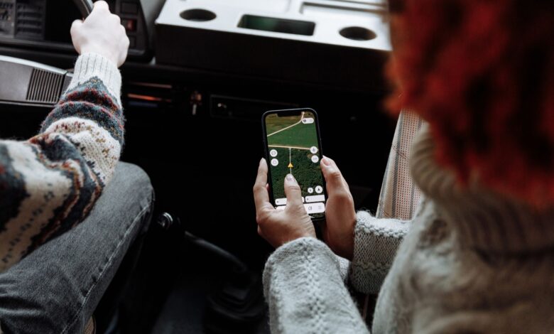 Two people using a navigation app on a smartphone during a road trip