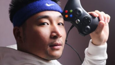 Asian man in white sweatshirt holding a gaming controller, focused on gaming.
