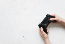 Close-up of hands holding a black game controller on a white background.