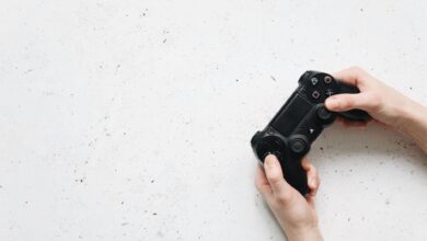 Close-up of hands holding a black game controller on a white background.