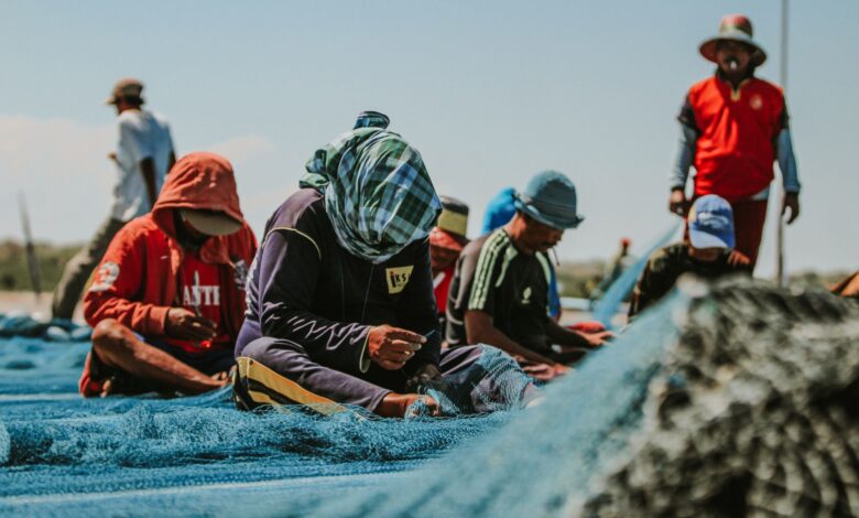Group of fishermen repairing nets on a sunny day in East Java, Indonesia.