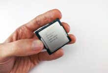 Close-up view of a hand holding an Intel Core i9 processor chip, showcasing technology details.