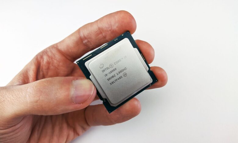 Close-up view of a hand holding an Intel Core i9 processor chip, showcasing technology details.