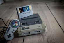 From above of aged video game console with cassette and controller with colorful buttons on wooden surface