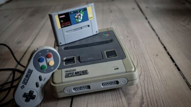 From above of aged video game console with cassette and controller with colorful buttons on wooden surface