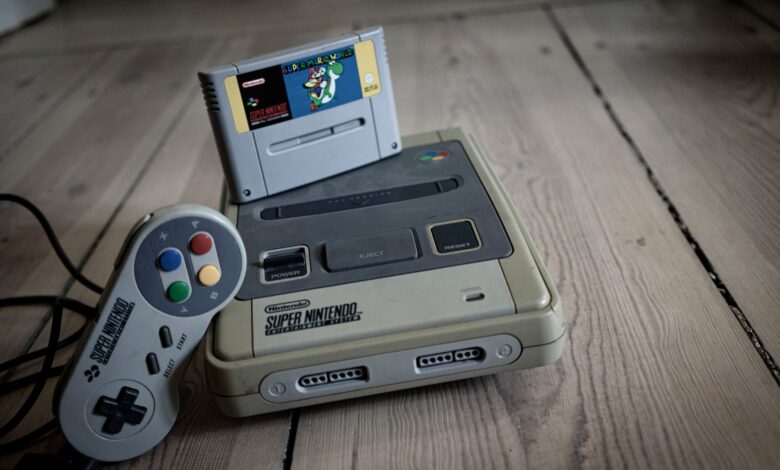 From above of aged video game console with cassette and controller with colorful buttons on wooden surface