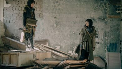 Two people exploring a desolate, abandoned building in post-apocalyptic attire.