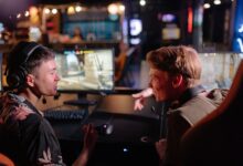 Two young men enjoying a lively video game session in a dimly lit gaming arena.