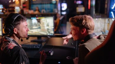 Two young men enjoying a lively video game session in a dimly lit gaming arena.