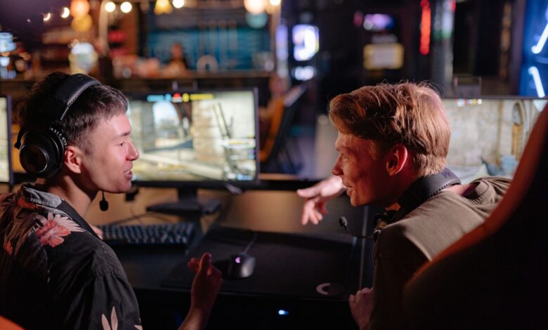 Two young men enjoying a lively video game session in a dimly lit gaming arena.