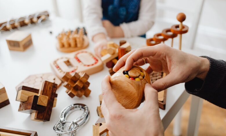 Close-up of hands engaging with wooden brain teasers on a table indoors.