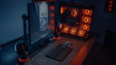 Sleek gaming desk setup featuring RGB lighting, large monitor, and gaming PC with glowing fans.