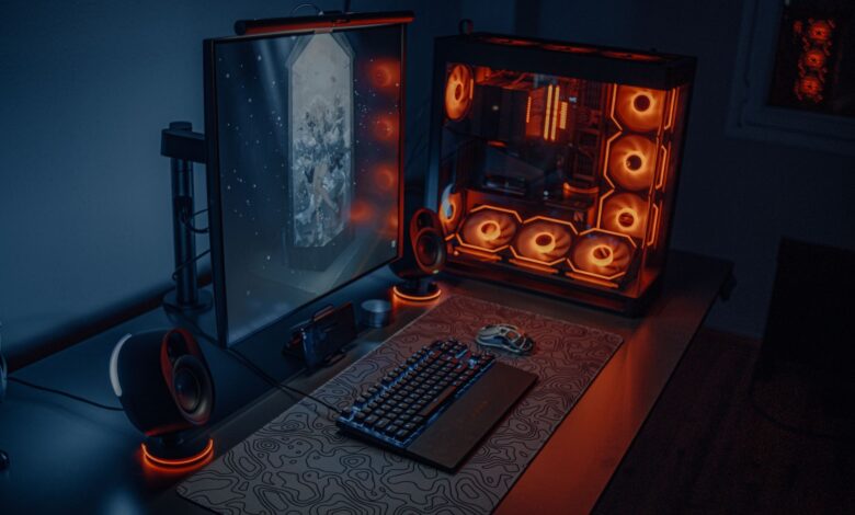 Sleek gaming desk setup featuring RGB lighting, large monitor, and gaming PC with glowing fans.