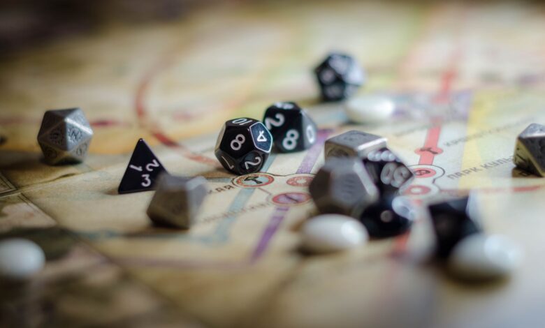 Focus on black and white polyhedral dice scattered on a board game map, suggesting strategy and chance.
