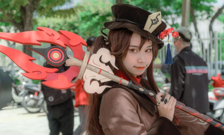 A female cosplayer dressed as Hu Tao from Genshin Impact poses outdoors with a detailed costume and weapon.