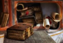 Close-up of a leather-bound antique book on a wooden table, with scrolls in the background, Moscow.
