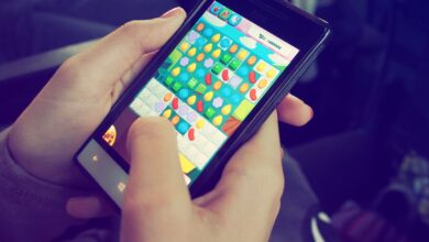 Hands holding a smartphone with a colorful puzzle game on the screen, displaying modern technology.