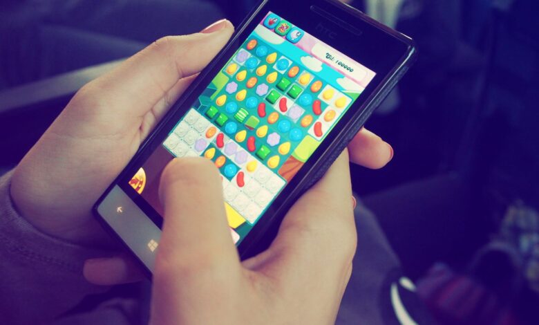 Hands holding a smartphone with a colorful puzzle game on the screen, displaying modern technology.