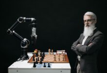 A robotic arm and a bearded man engaged in a strategic chess game highlighting technology and innovation.