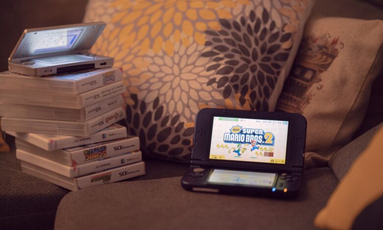 Two handheld gaming consoles on a sofa with game cartridges, creating a cozy game night mood.